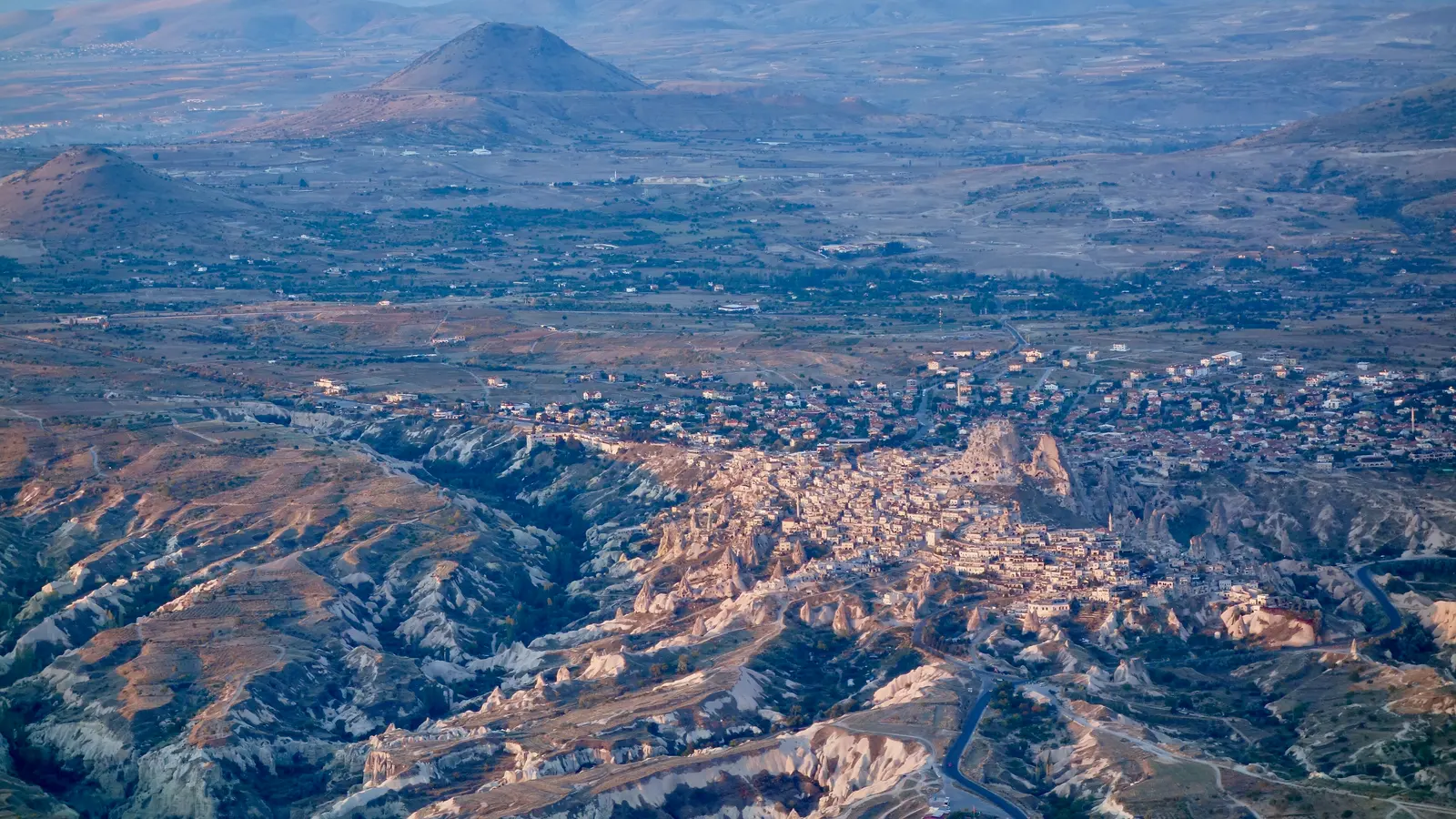 Uçhisar çevresinde gün doğumunda sıcak hava balonları ve vadi manzarası.