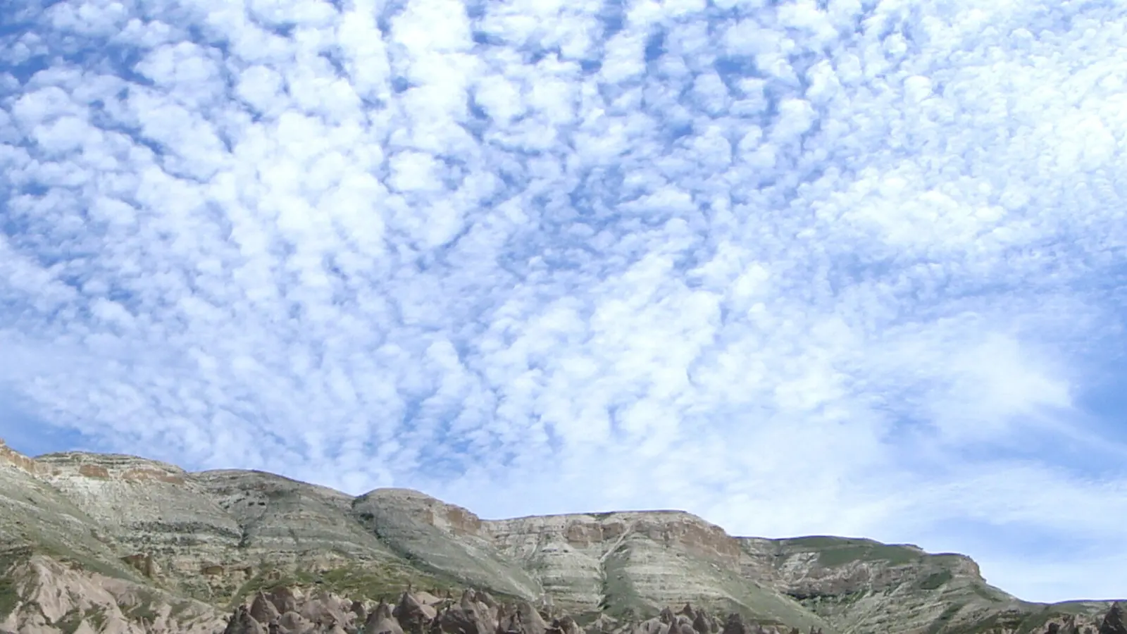 Kapadokya'da bulutlu gökyüzü ve kaya sırtlarının panoraması.